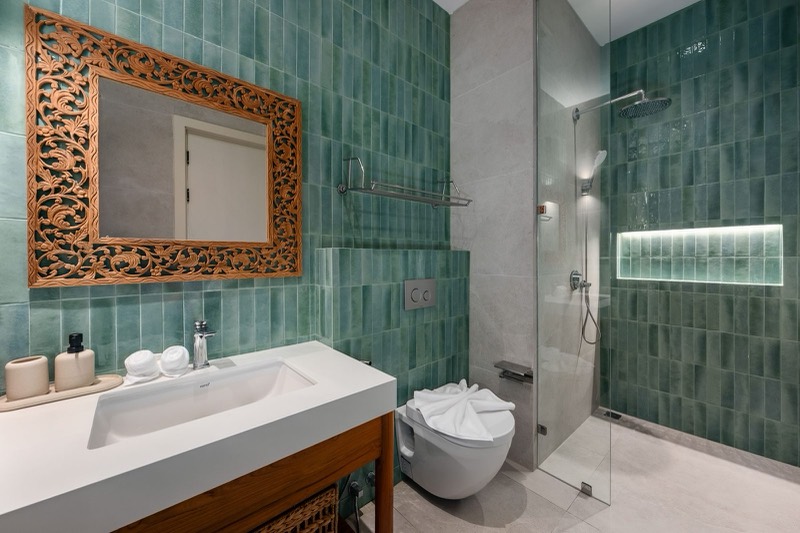 Bathroom with green tile, carved teak mirror and walk-in shower