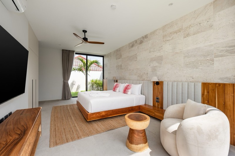 Master bedroom with travertine feature wall and a round armchair