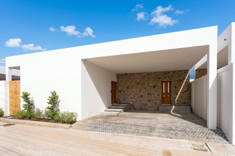The white entrance portico with stone wall and parking