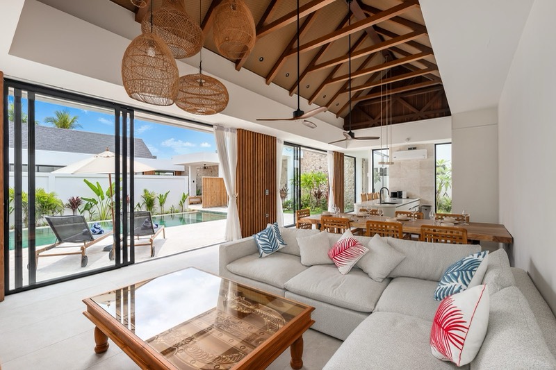 Living room with L-shaped sofa, timber roof and rattan pendant lights